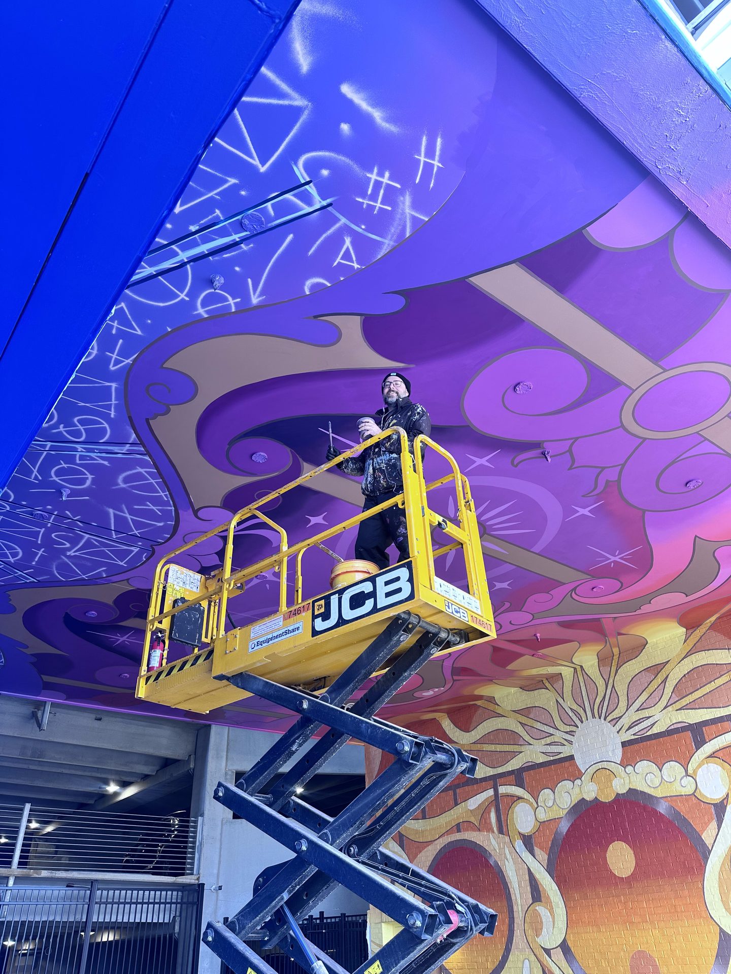 Adam Stephenson painting the Upton ceiling from a lift, process shot, Atlanta