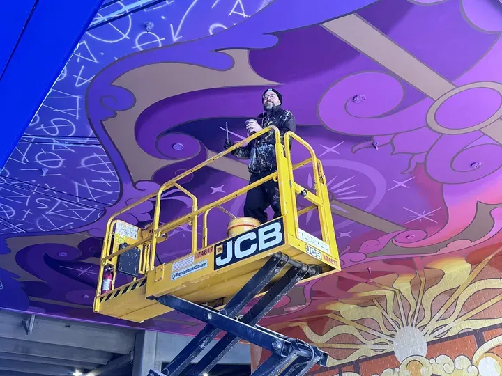 Adam Stephenson on a scissor lift painting the ceiling of The Hall of the Magician